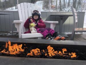 Girls sitting in front of fire snacking at Saskadena Six in Vermont